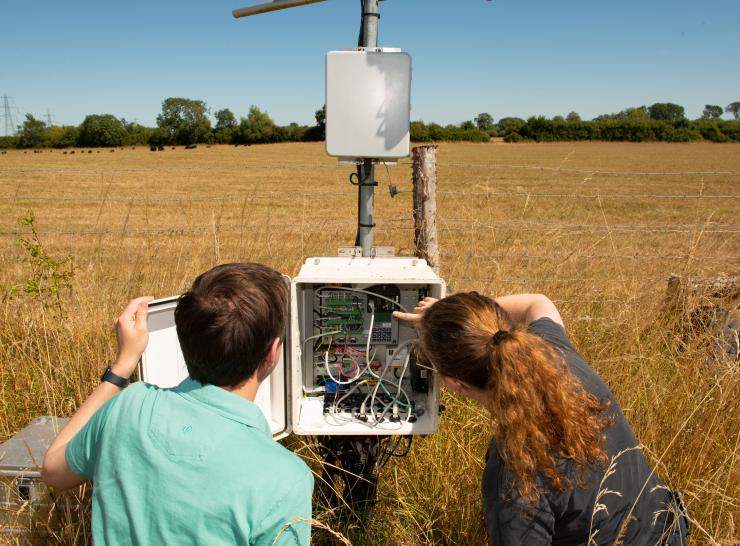 Two people looking at a COSMOS-UK logger box